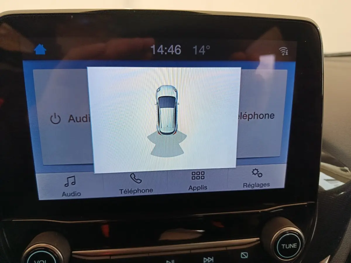 Écran tactile central du Ford Puma montrant la vue aérienne du véhicule blanc en stationnement.