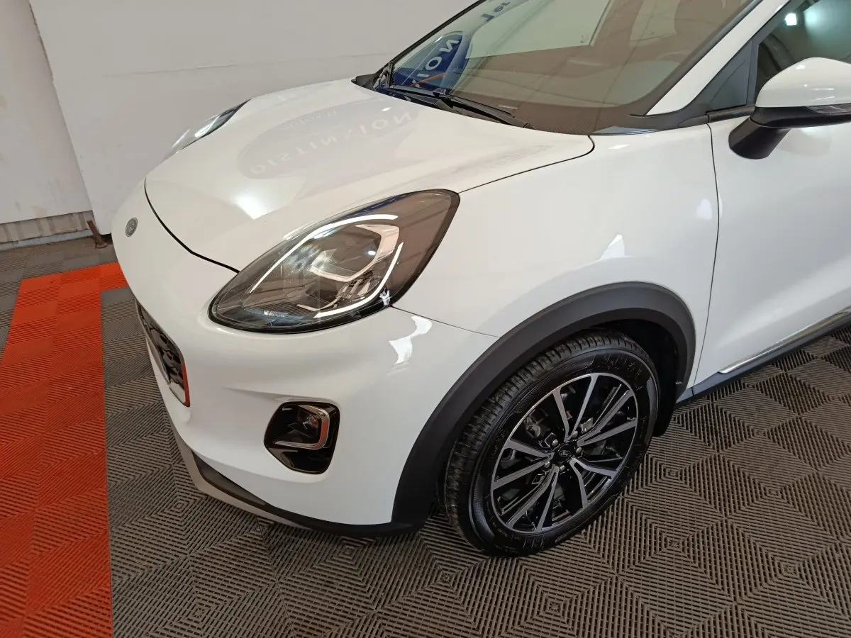 Vue 3/4 avant droit d'une Ford Puma blanche avec phares LED et jantes alliage noires brillantes.