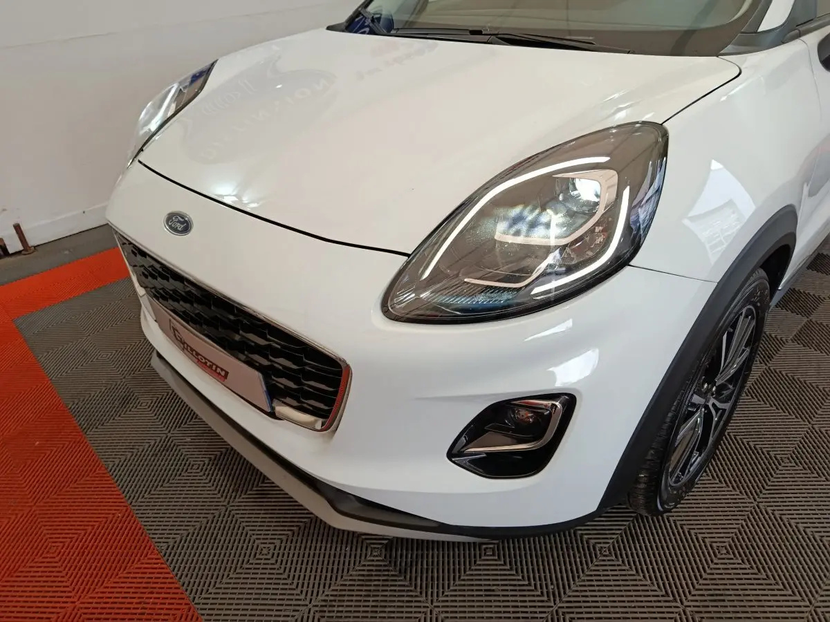Vue 3/4 avant droit d'une Ford Puma blanche avec phares LED et calandre noire brillante.