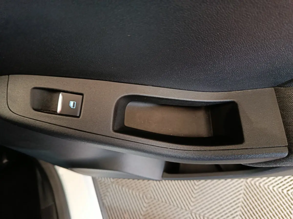 Gros plan sur la commande de lève-vitre côté conducteur d'une Ford Puma blanche, intérieur noir.