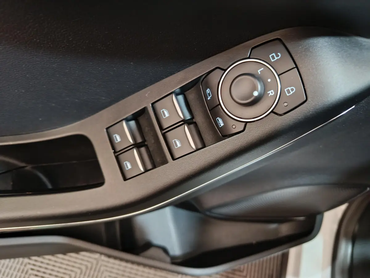 Gros plan sur les commandes de lève-vitres et rétroviseurs côté conducteur du Ford Puma blanc 2022.