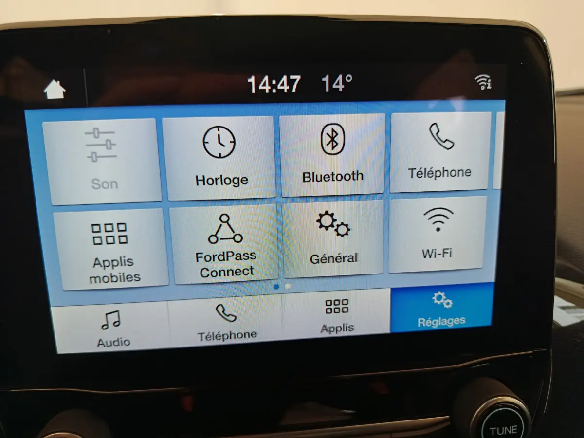 Écran tactile central affichant le menu des réglages dans l’habitacle d’une Ford Puma blanche, vue de face.