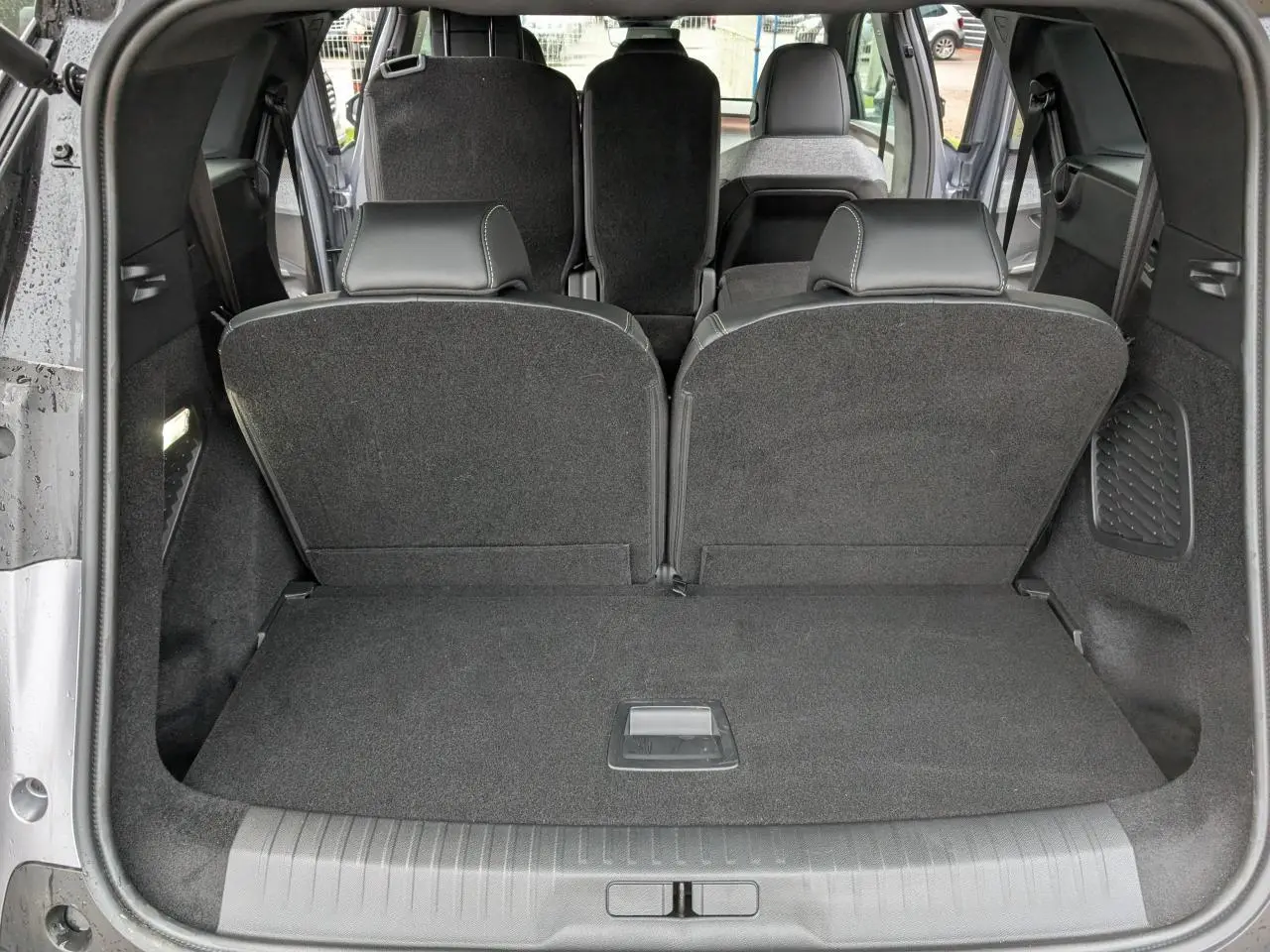 Vue arrière du coffre du Peugeot 5008 gris avec banquette 3e rang rabattue et sièges 2e rang visibles.