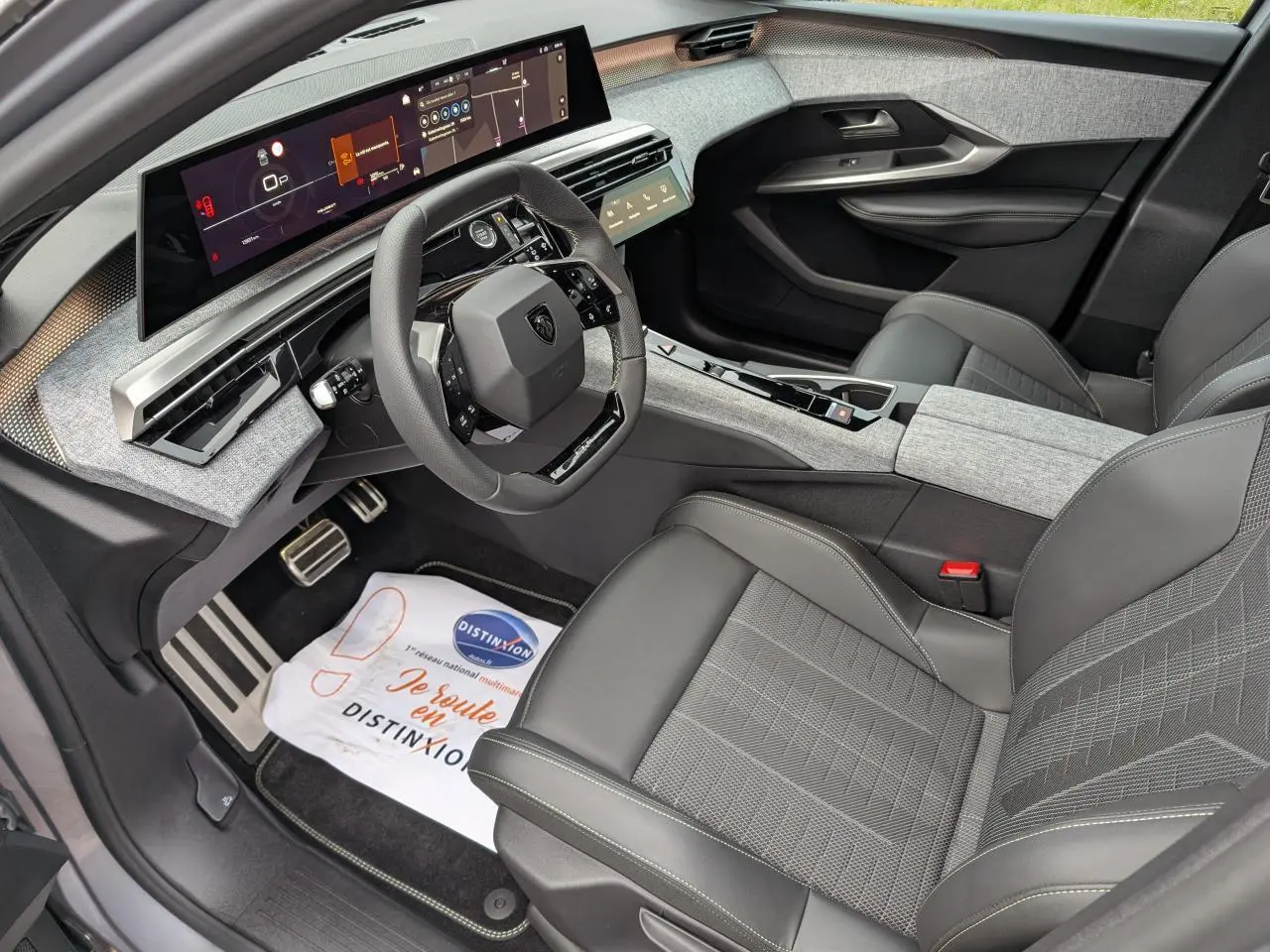Vue intérieure côté conducteur du Peugeot 5008 gris 2025, avec tableau de bord numérique panoramique et sellerie tissu gris.