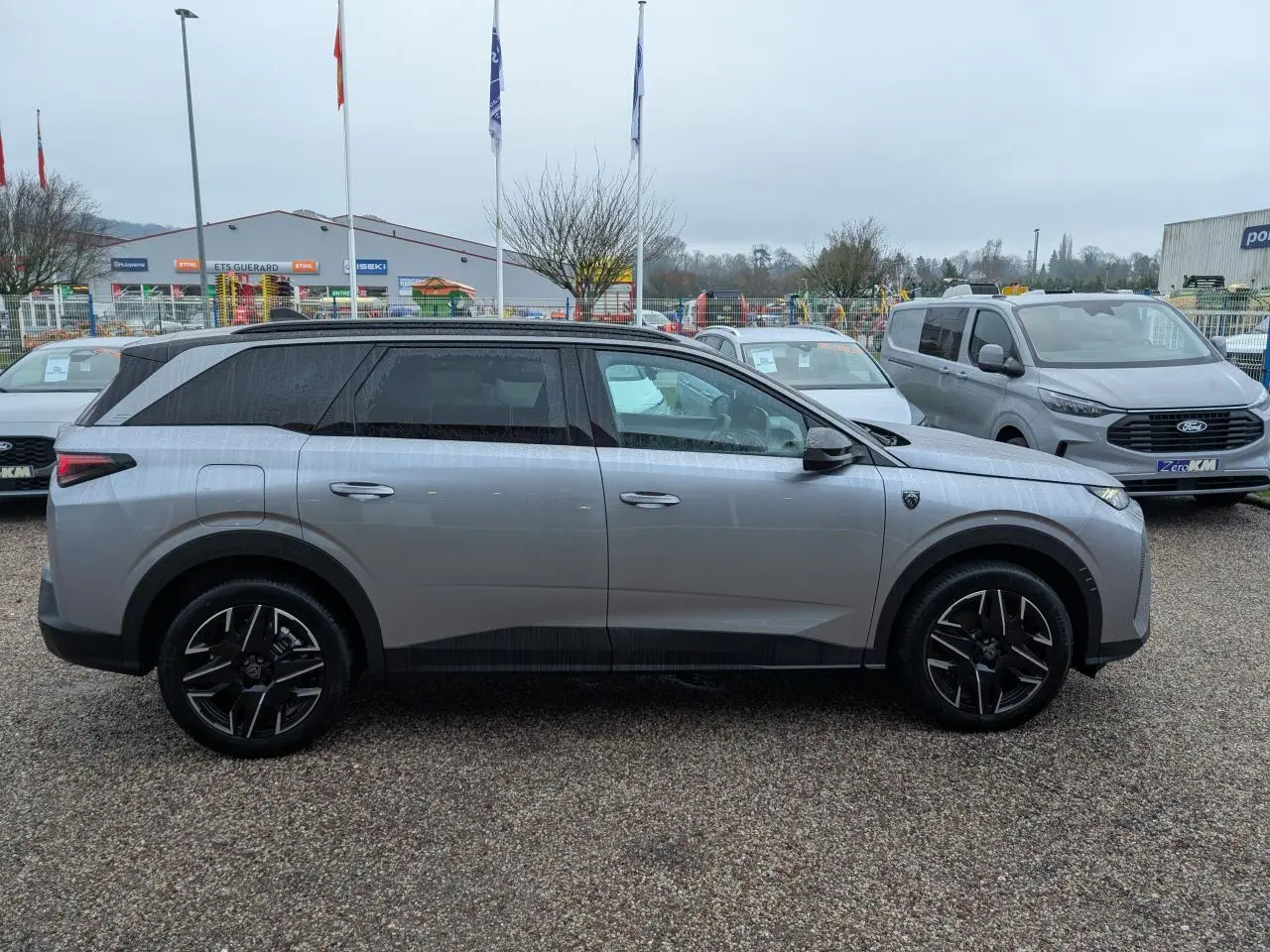 Peugeot 5008 gris métallisé vue de profil côté gauche, avec jantes alliage noires et toit noir.