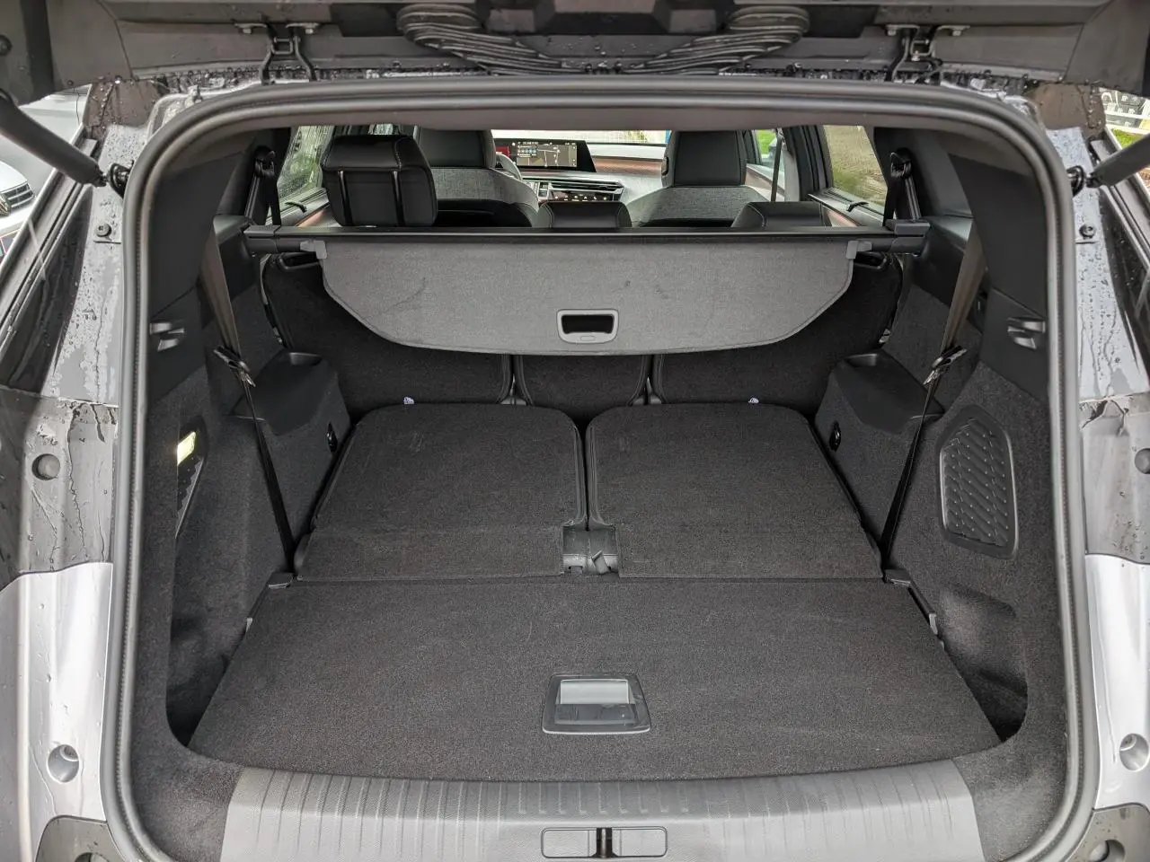 Coffre ouvert du Peugeot 5008 gris, banquette arrière rabattue offrant un espace de chargement plat et spacieux.
