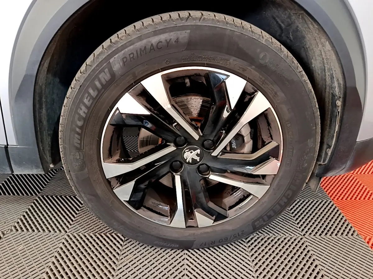 Gros plan sur la roue avant droite du Peugeot 2008 gris clair, avec jante alliage noire et argentée distinctive.