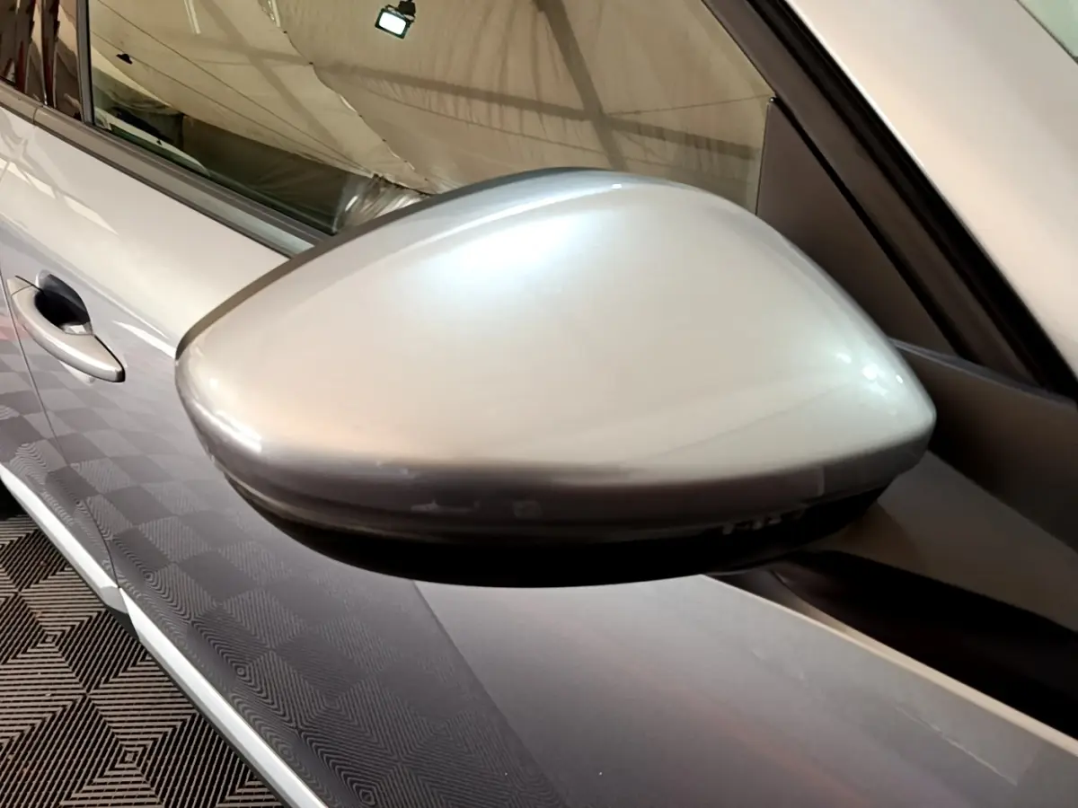 Gros plan sur le rétroviseur droit gris clair du Peugeot 2008, avec la portière et poignée visibles en arrière-plan.