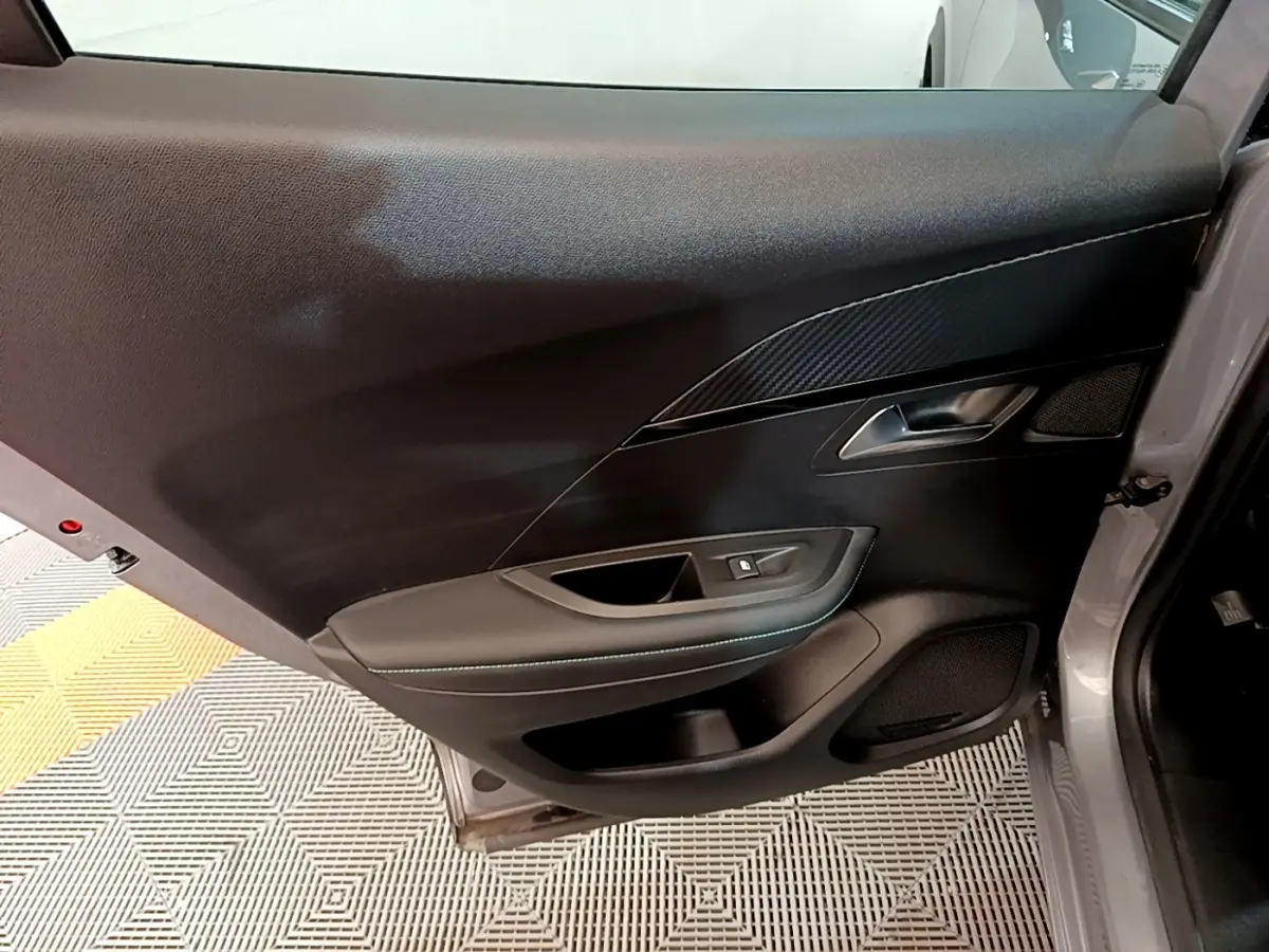 Vue intérieure de la porte arrière gauche gris clair du Peugeot 2008 avec garniture noire et poignée métallique.