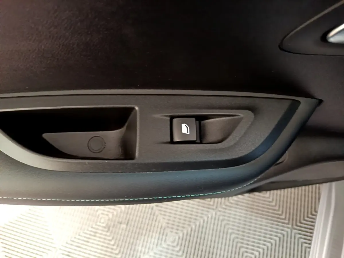 Gros plan sur la commande de lève-vitre côté gauche intérieur d’un Peugeot 2008 gris clair de 2021.