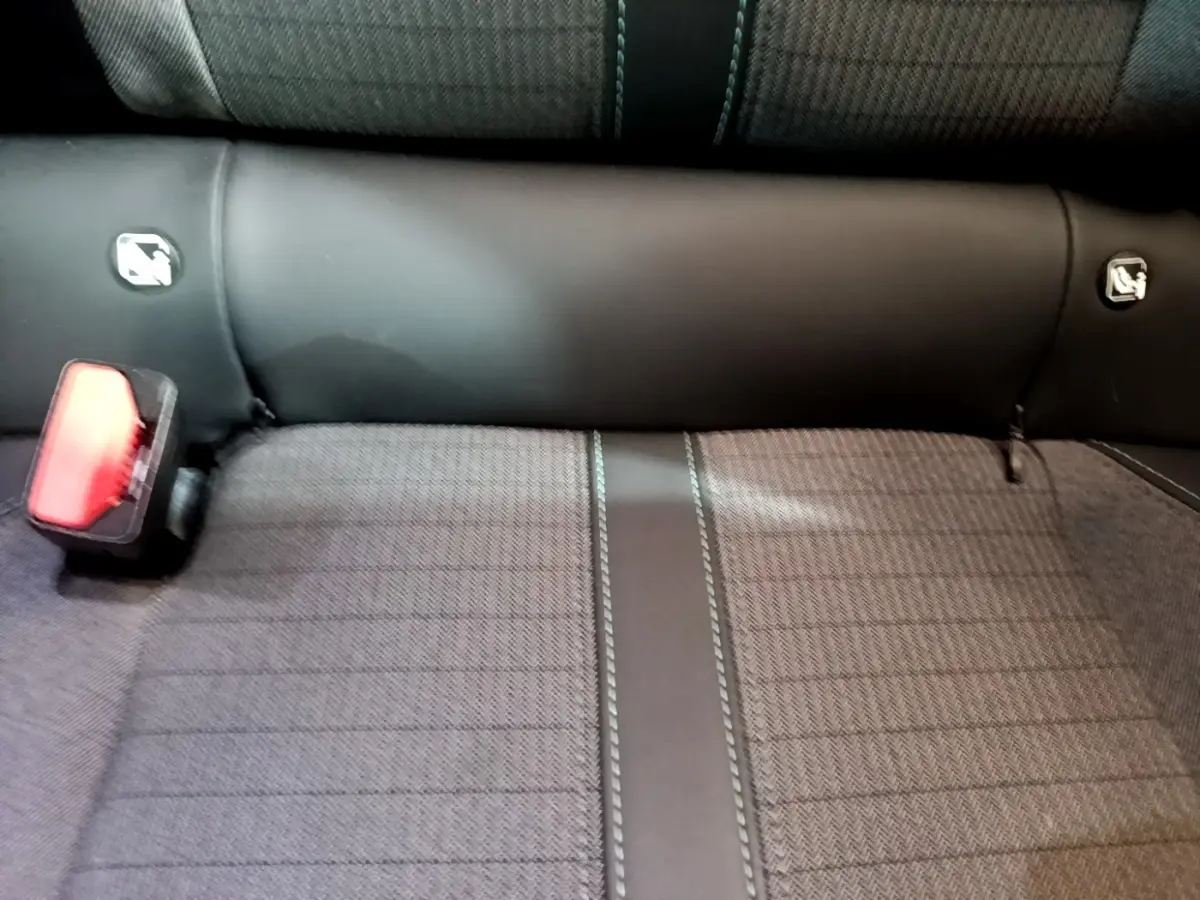 Gros plan sur la banquette arrière gris foncé du Peugeot 2008 avec ceinture de sécurité rouge visible à gauche.