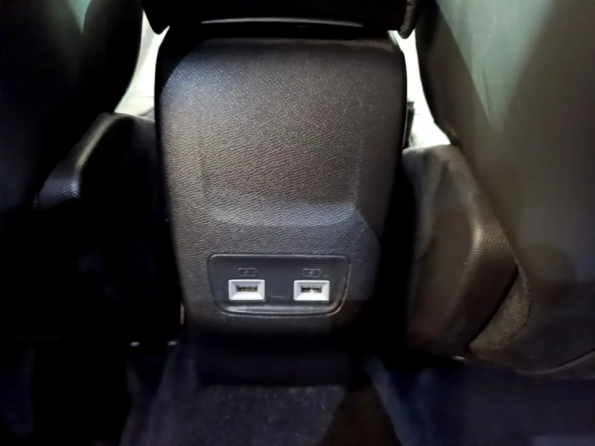 Prise double USB arrière sur console centrale noire du Peugeot 2008 gris clair, vue rapprochée du plancher arrière.