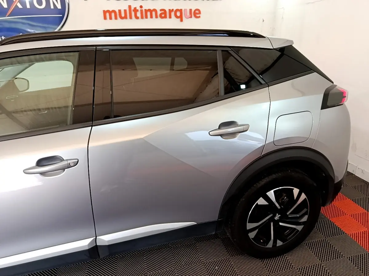 Vue latérale droite du Peugeot 2008 gris clair, mettant en valeur les vitres teintées et les jantes noires à motifs argentés.