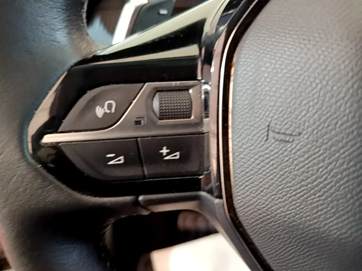 Gros plan sur les commandes vocales et volume au volant cuir noir du Peugeot 2008 gris clair, version 2021.