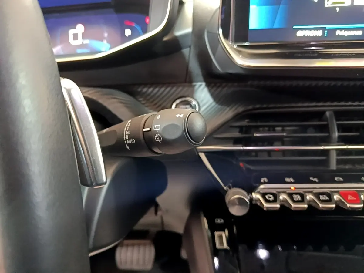 Gros plan sur la commande d’essuie-glace à gauche du volant dans l’habitacle gris clair du Peugeot 2008 2021.
