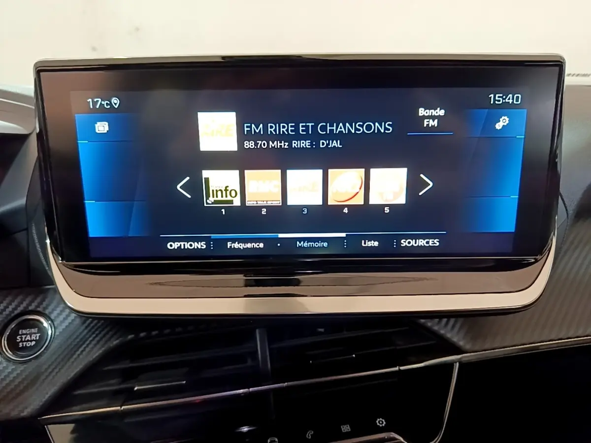 Écran tactile central affichant la radio FM dans l’habitacle du Peugeot 2008 gris clair, vue rapprochée du tableau de bord.