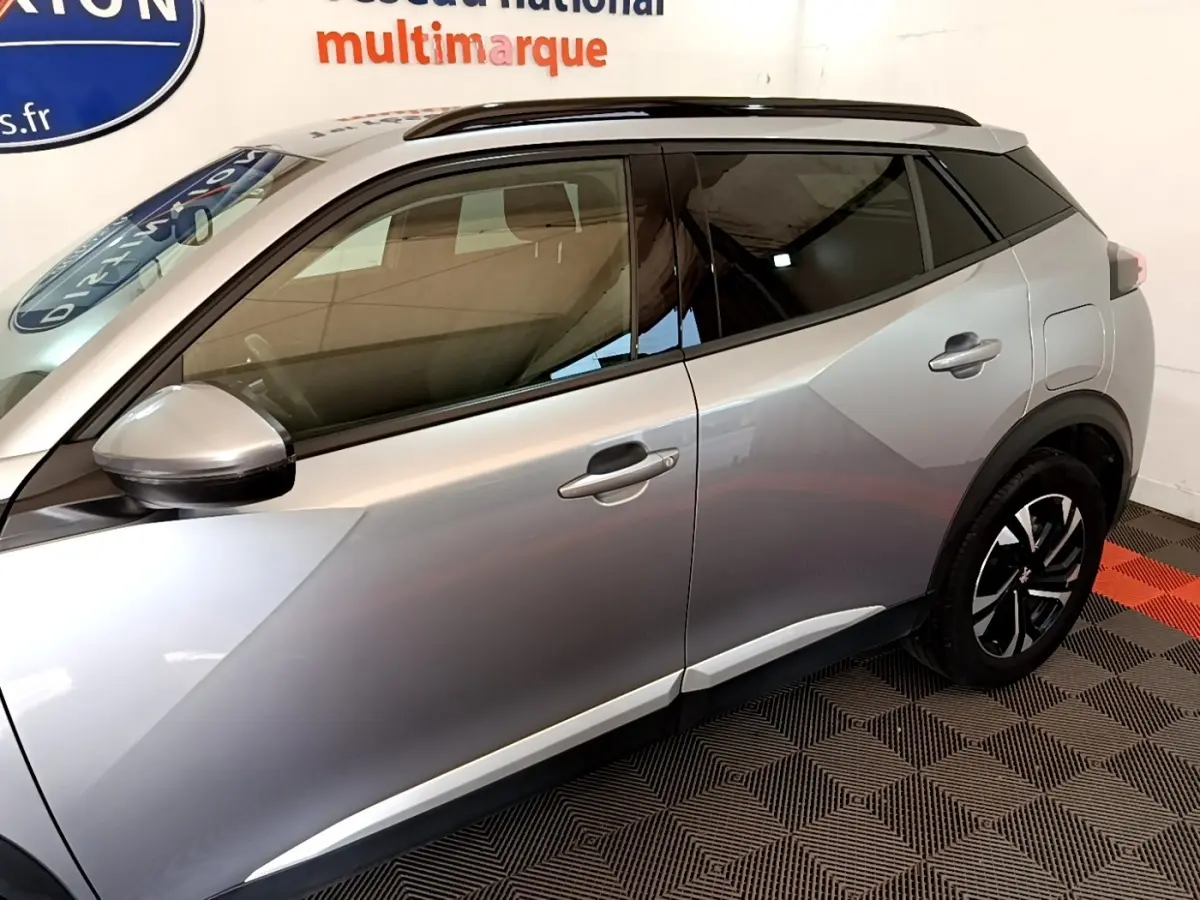 Vue latérale côté gauche d'un Peugeot 2008 gris clair avec rétroviseurs électriques et jantes noires.