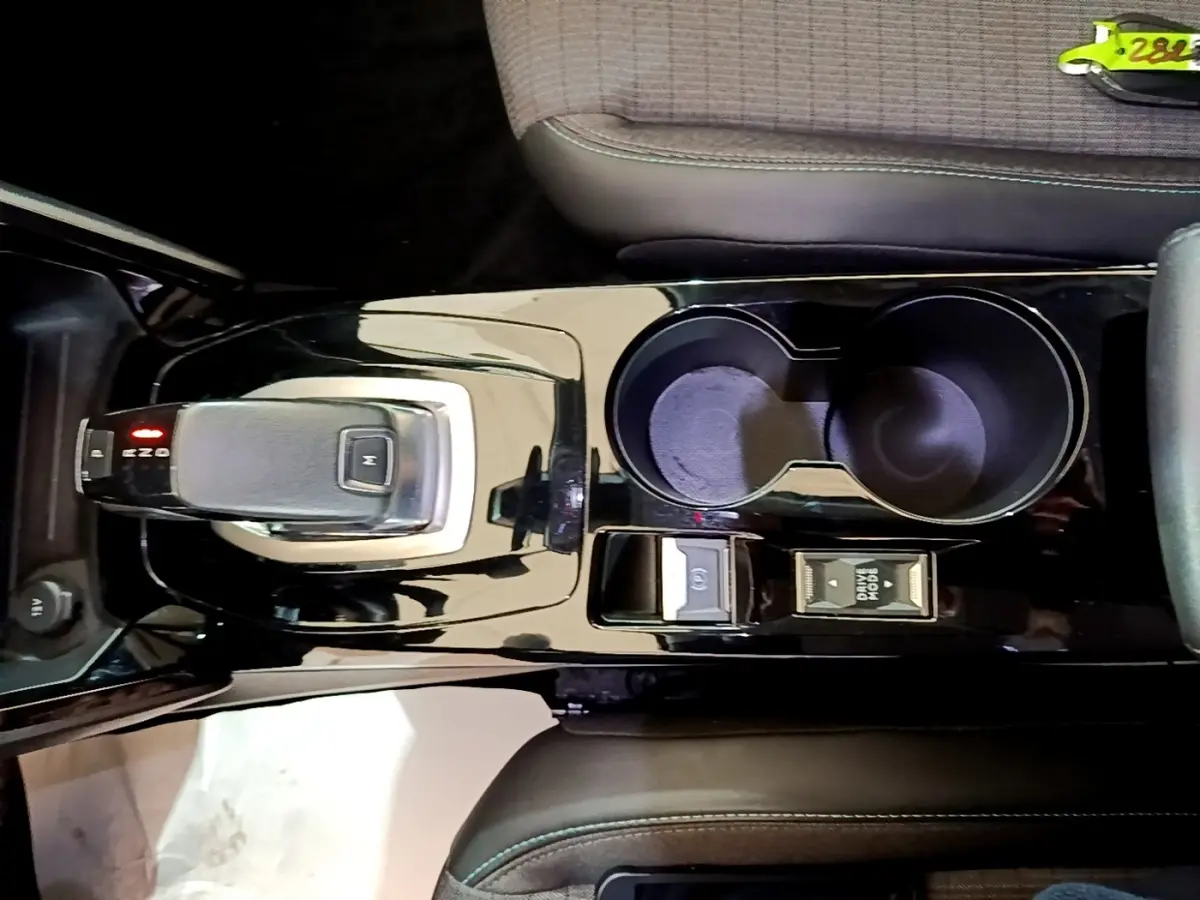 Vue plongeante sur la console centrale noire brillante du Peugeot 2008 avec levier de vitesse automatique et porte-gobelets.