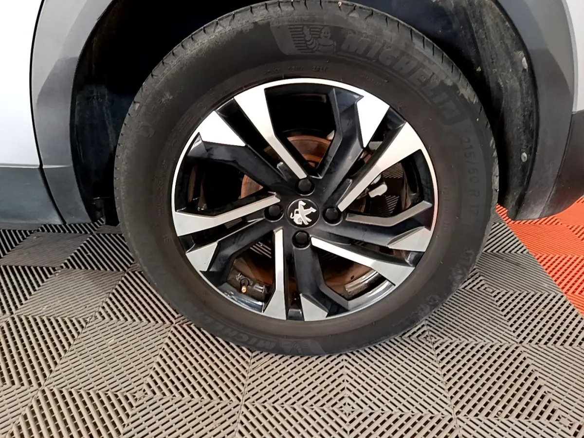 Gros plan sur la roue avant gauche avec jante alliage bicolore noir et argent du Peugeot 2008 gris clair.