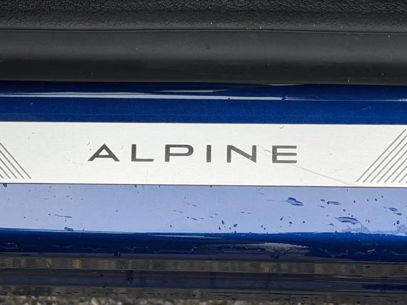 Gros plan sur la plaque Alpine en blanc sur le seuil de porte bleu Iron du Renault Captur 1.8 E-Tech hybride 2026.
