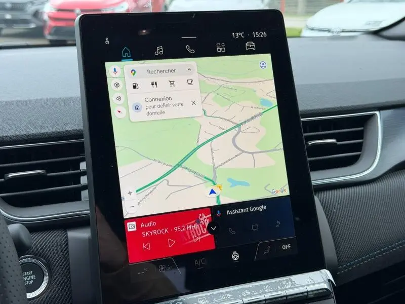 Écran tactile central du Renault Captur 2026 affichant la navigation Google Maps et la radio Skyrock, intérieur noir avec surpiqûres bleues.