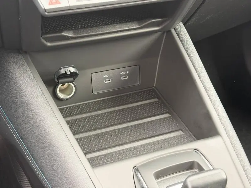 Détail de la console centrale du Renault Captur 2026, montrant prises USB-C et prise 12V, finition intérieure noire avec surpiqûres bleues.