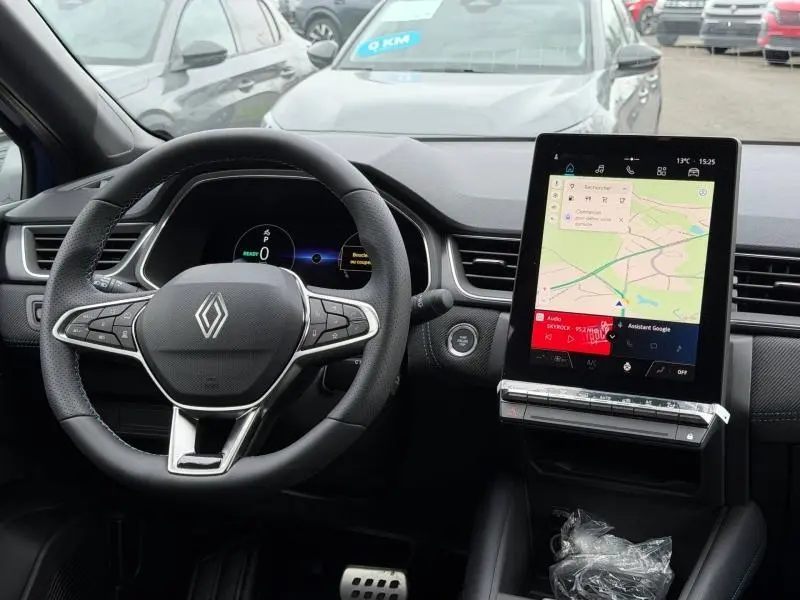 Vue intérieure du tableau de bord du Renault Captur 2026 hybride, avec volant multifonction et écran tactile central vertical.