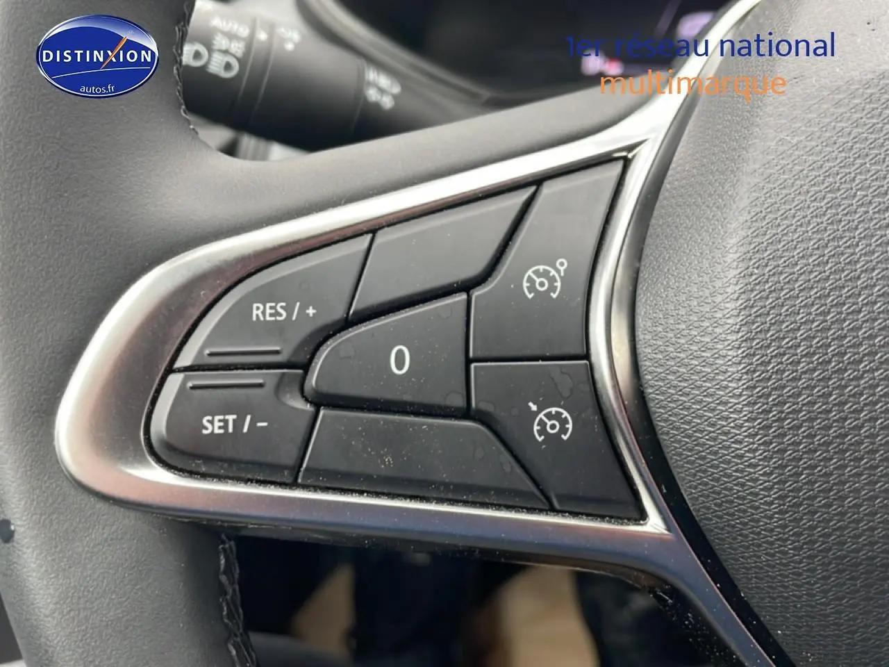 Gros plan sur les commandes de régulateur de vitesse au volant d’une Renault Clio V blanche, version 2025.