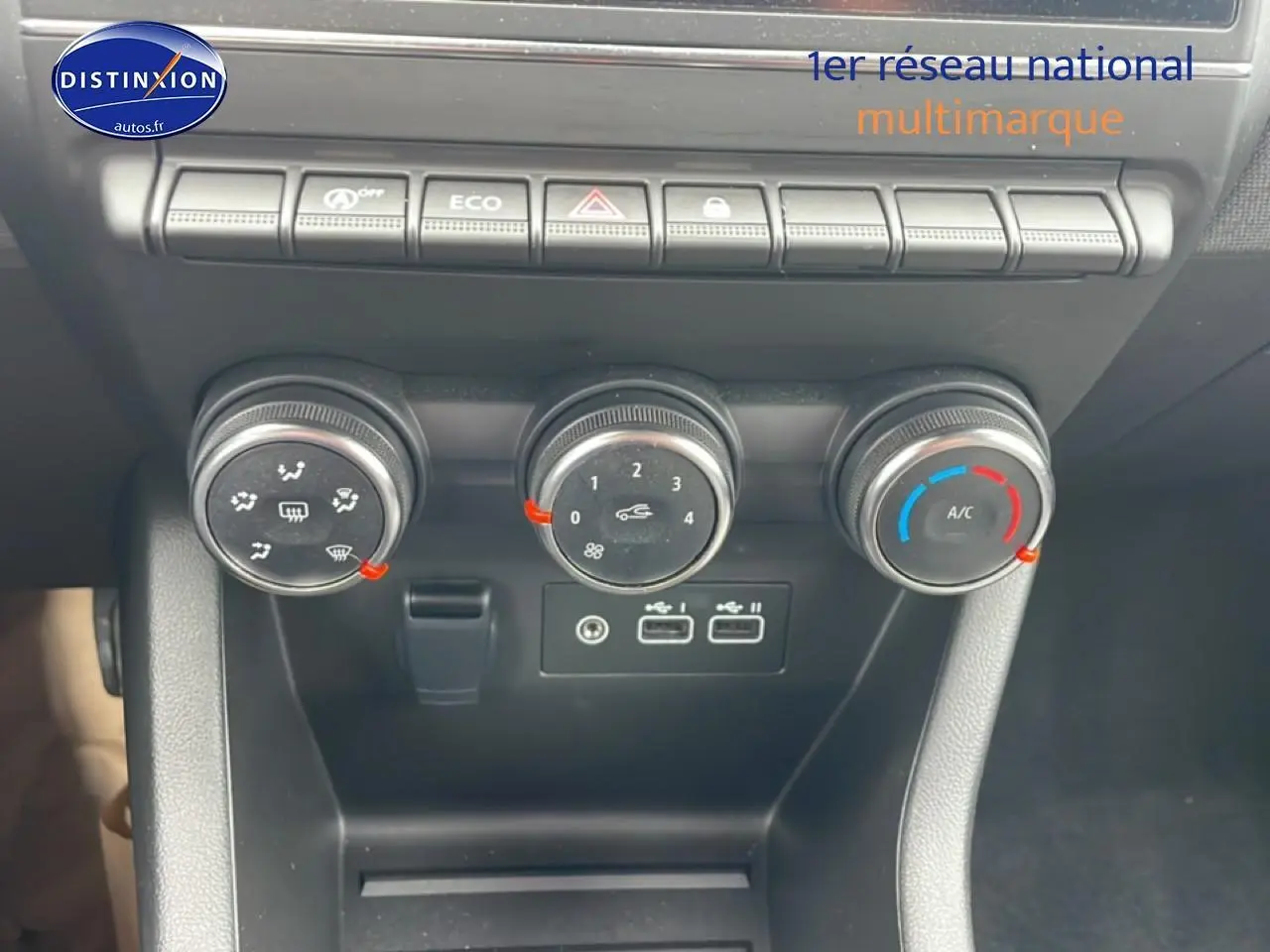 Gros plan sur la console centrale de la Renault Clio V blanche, montrant les commandes de climatisation et ports USB.