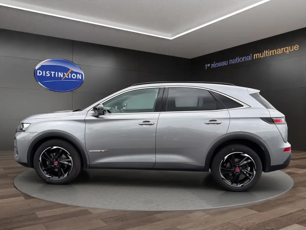 Vue de profil côté gauche du SUV DS7 Crossback gris clair avec jantes noires et détails chromés.