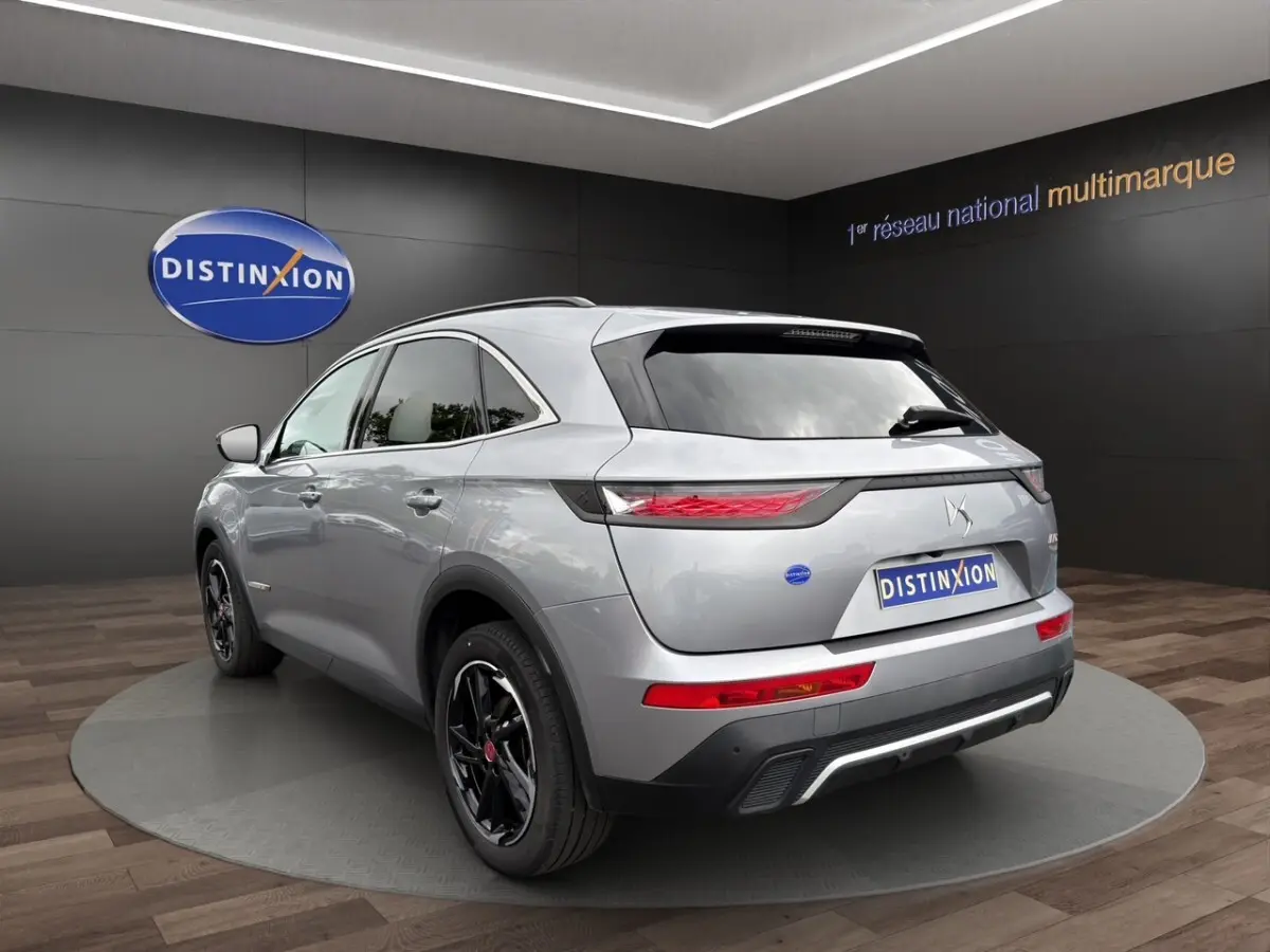 DS7 Crossback gris clair vu en 3/4 arrière droit, avec jantes noires et feux arrière LED distinctifs.