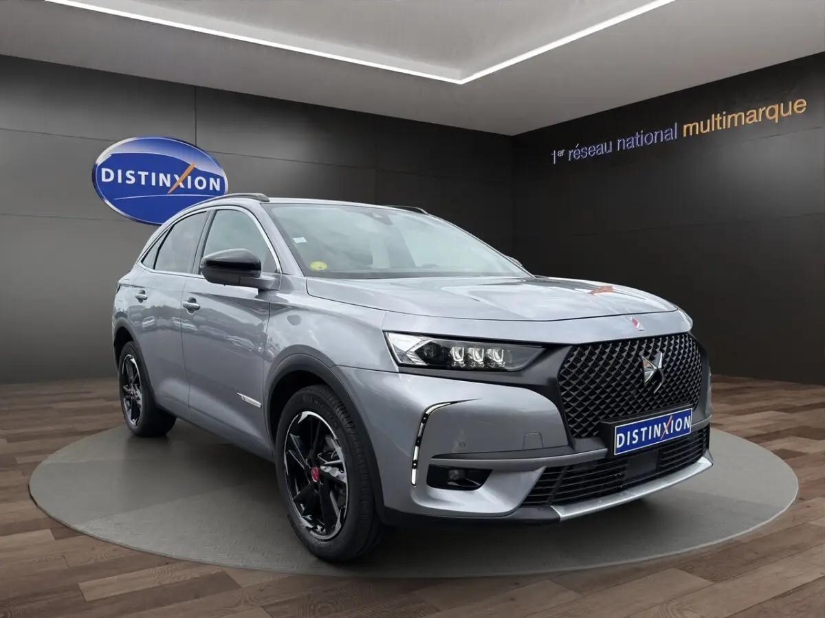 DS7 Crossback gris clair en 3/4 avant droit, avec calandre noire et jantes noires brillantes distinctives.