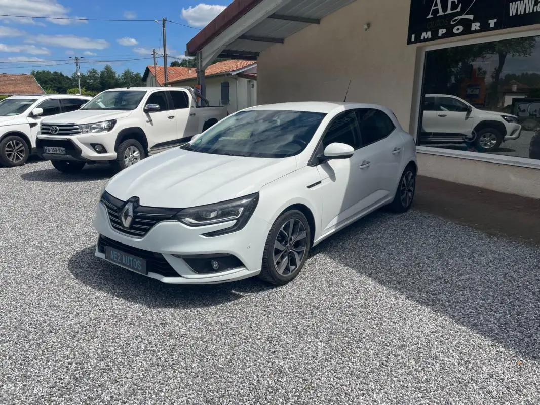 Renault Mégane IV blanche vue en 3/4 avant droit, avec jantes alliage et calandre noire distinctive.