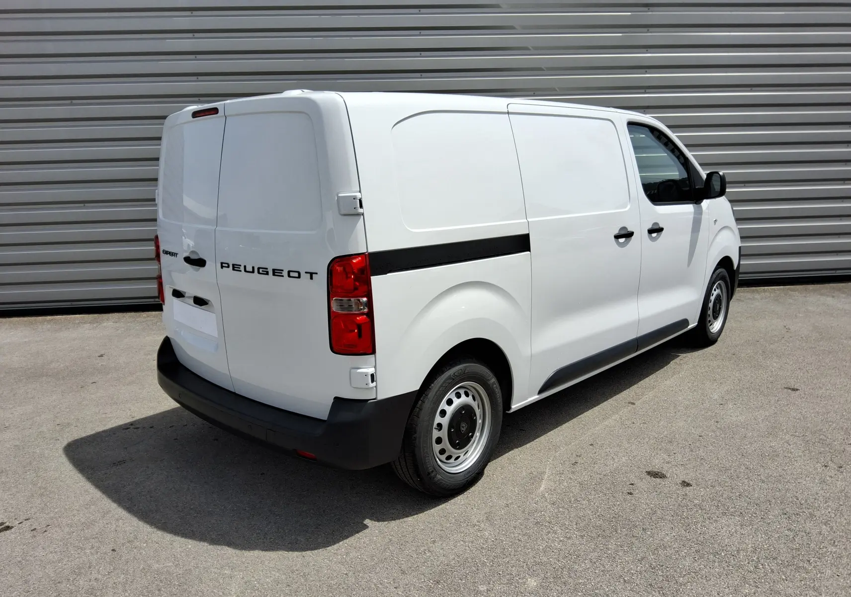 Vue 3/4 arrière droite du fourgon utilitaire Peugeot Expert blanc avec bande noire latérale et feux arrière rouges.