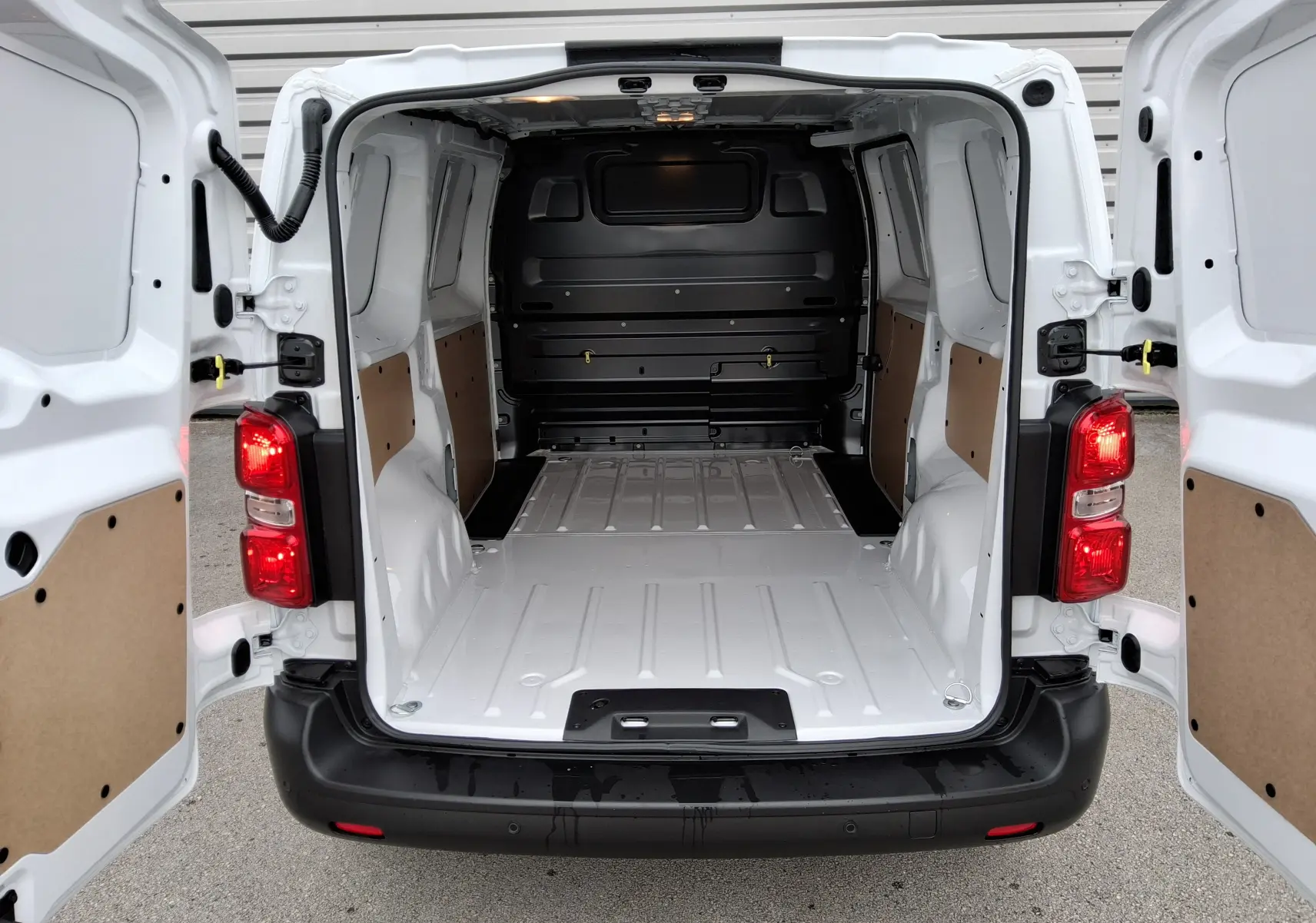 Vue arrière du Peugeot Expert Fourgon blanc 2025 avec portes ouvertes montrant la grande zone de chargement vide et protégée.