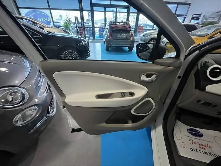Vue intérieure côté gauche de la porte avant blanche glacée d'une Renault ZOE R90 LIFE 41 KWh en concession.
