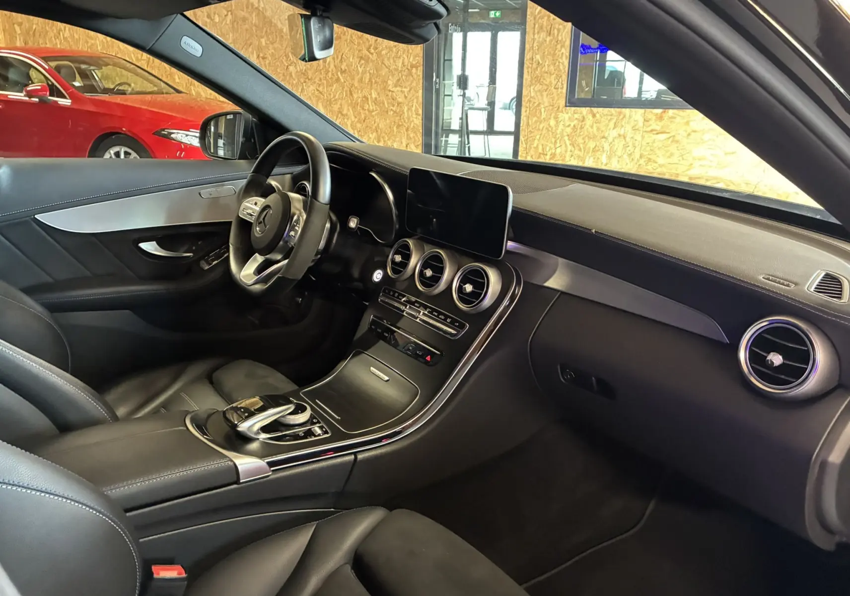 Vue intérieure côté conducteur de la Mercedes Classe C Break 220D noir métal, avec tableau de bord et volant cuir multifonction.