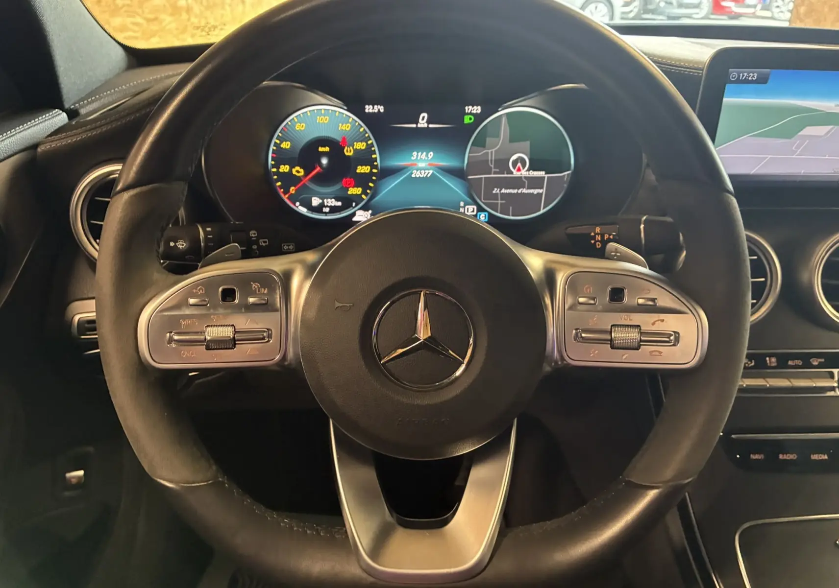 Vue rapprochée du volant cuir multifonction et du tableau de bord digital du Mercedes Classe C Break noir métal 220D AMG Line.