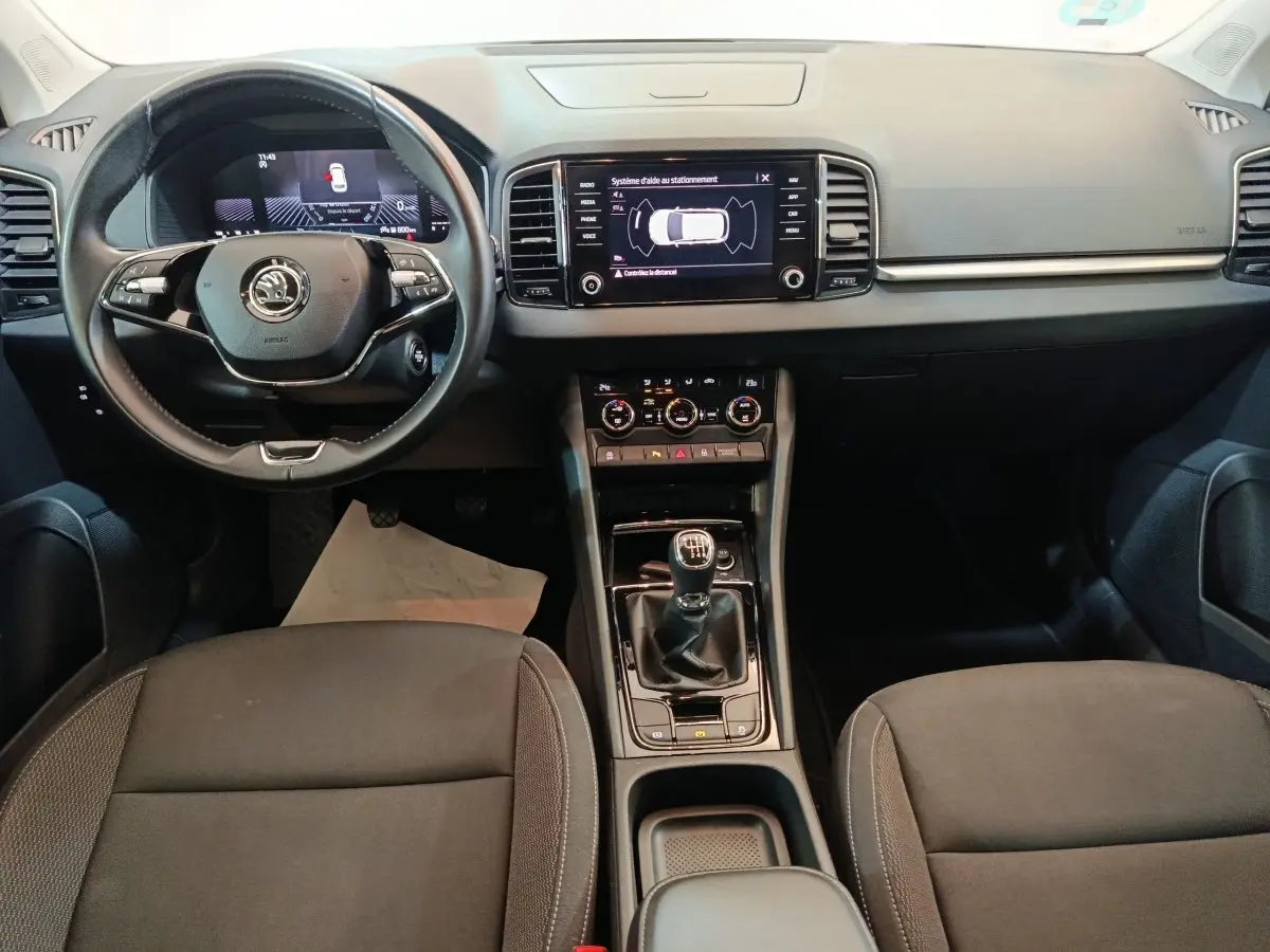 Vue intérieure frontale du tableau de bord noir et volant cuir d’une Skoda Karoq 2024 avec boîte manuelle.
