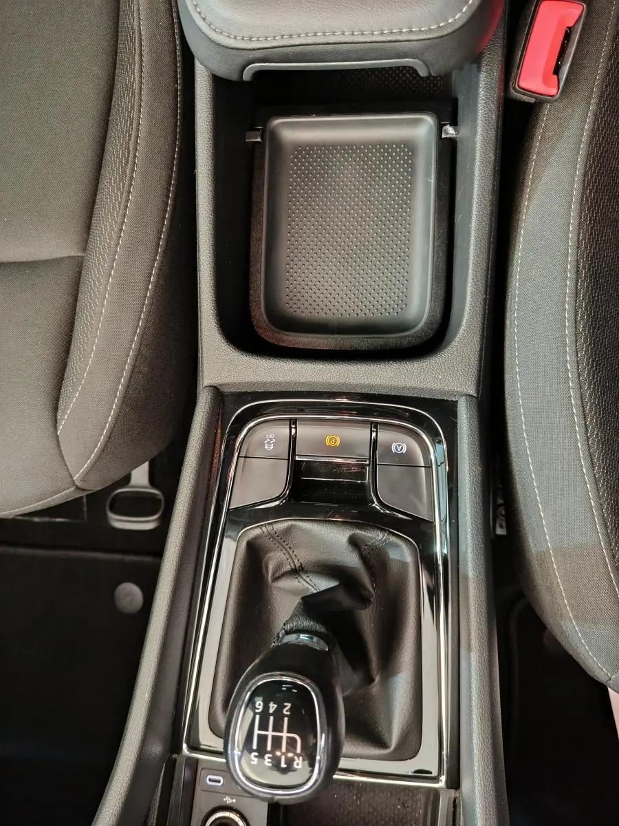 Vue plongeante sur la console centrale noire du Skoda Karoq 2024, mettant en valeur le levier de vitesse manuel et le frein à main électrique.