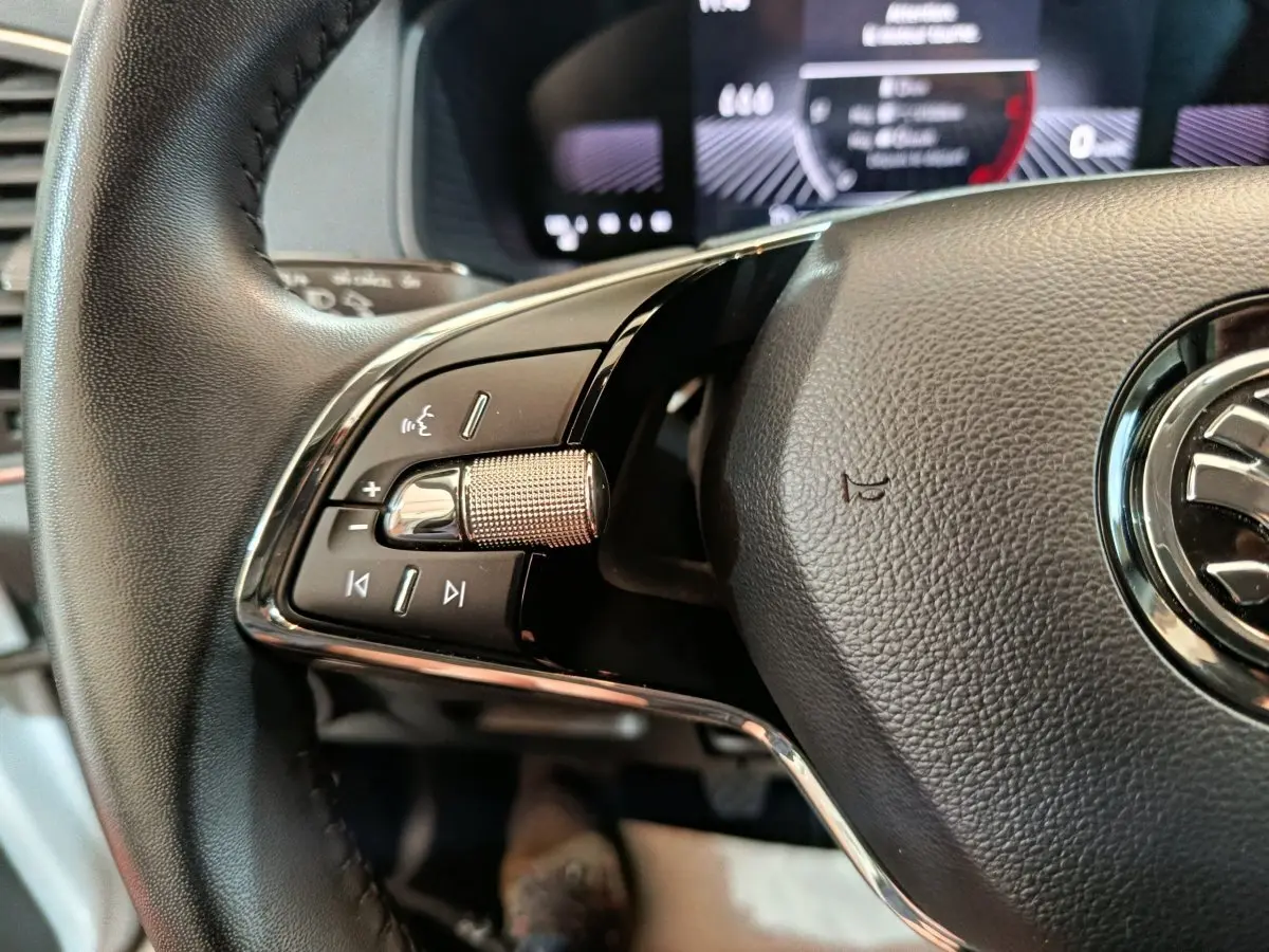 Gros plan sur la partie gauche du volant cuir noir d'un Skoda Karoq 2024 avec commandes multimédia intégrées.