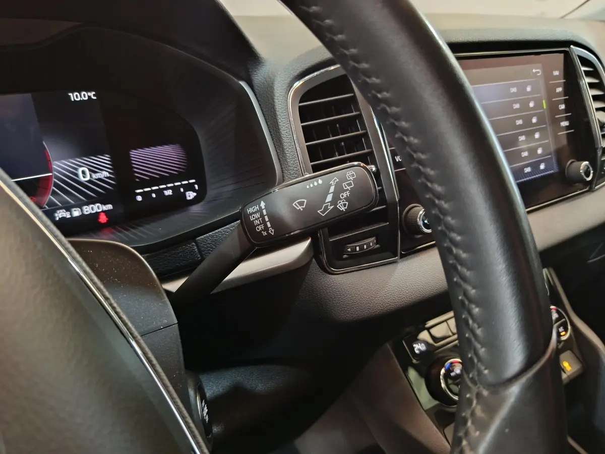 Gros plan intérieur sur le tableau de bord et le volant cuir noir du Skoda Karoq 2024, avec affichage digital et commandes au volant.