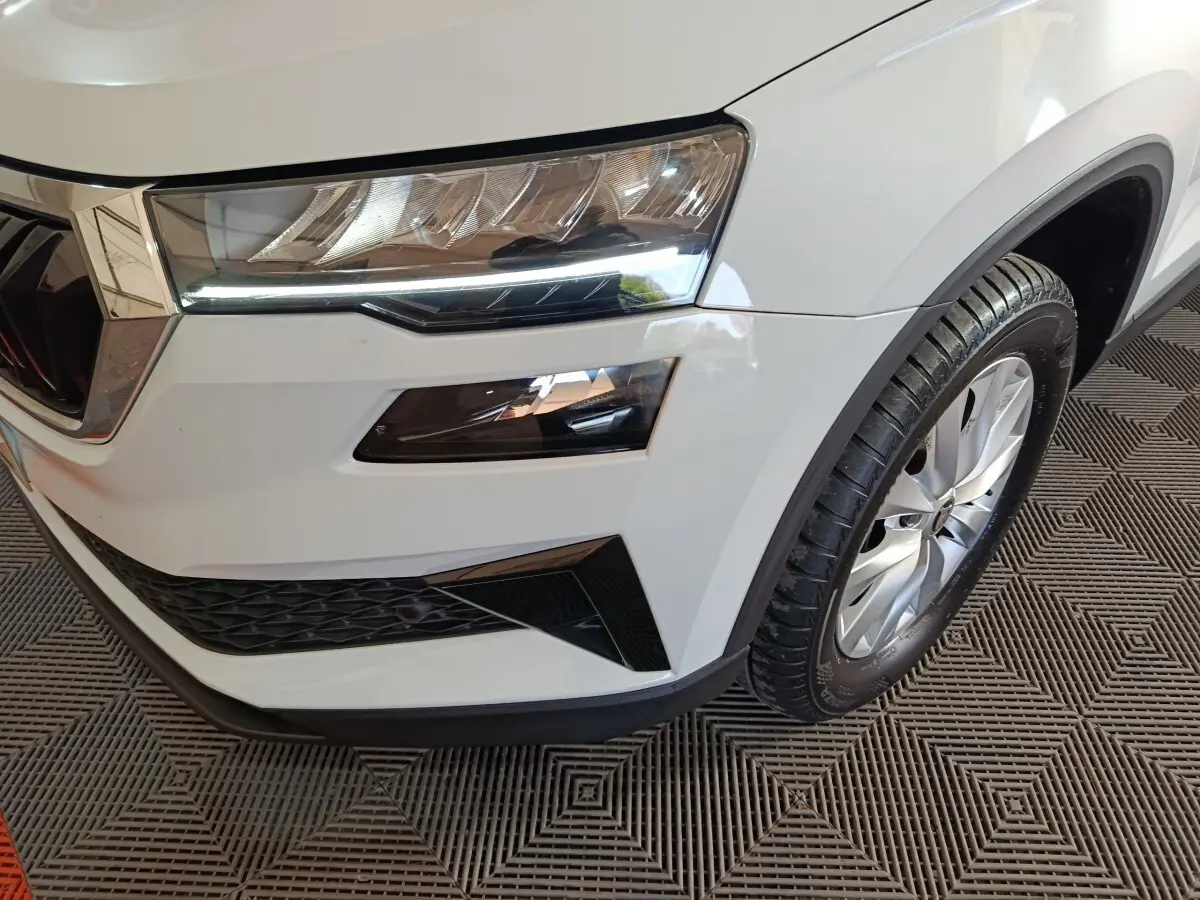 Gros plan sur l'avant droit blanc du Skoda Karoq 2024, mettant en valeur le phare LED et la roue alliage.