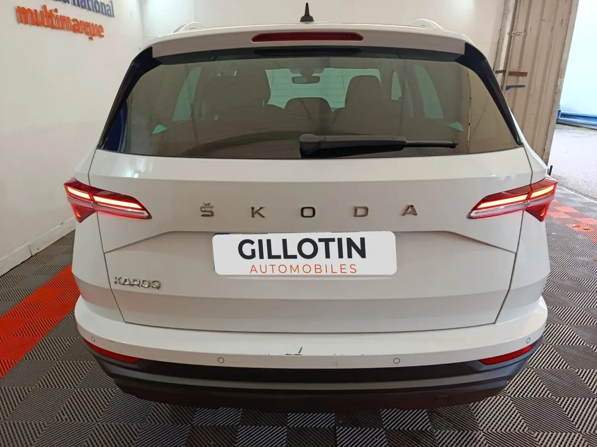 Vue arrière d'un Skoda Karoq blanc avec feux LED allumés et logo ŠKODA bien visible.