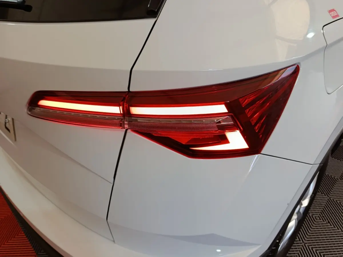 Gros plan sur le feu arrière droit allumé d’un Skoda Karoq blanc, mettant en valeur ses lignes LED modernes.