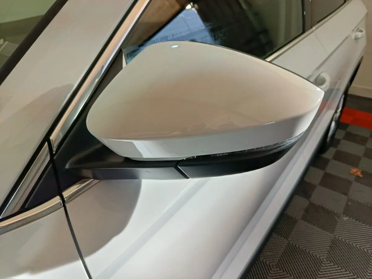 Rétroviseur côté gauche blanc du Skoda Karoq 2024, avec clignotant intégré et carrosserie visible en arrière-plan.