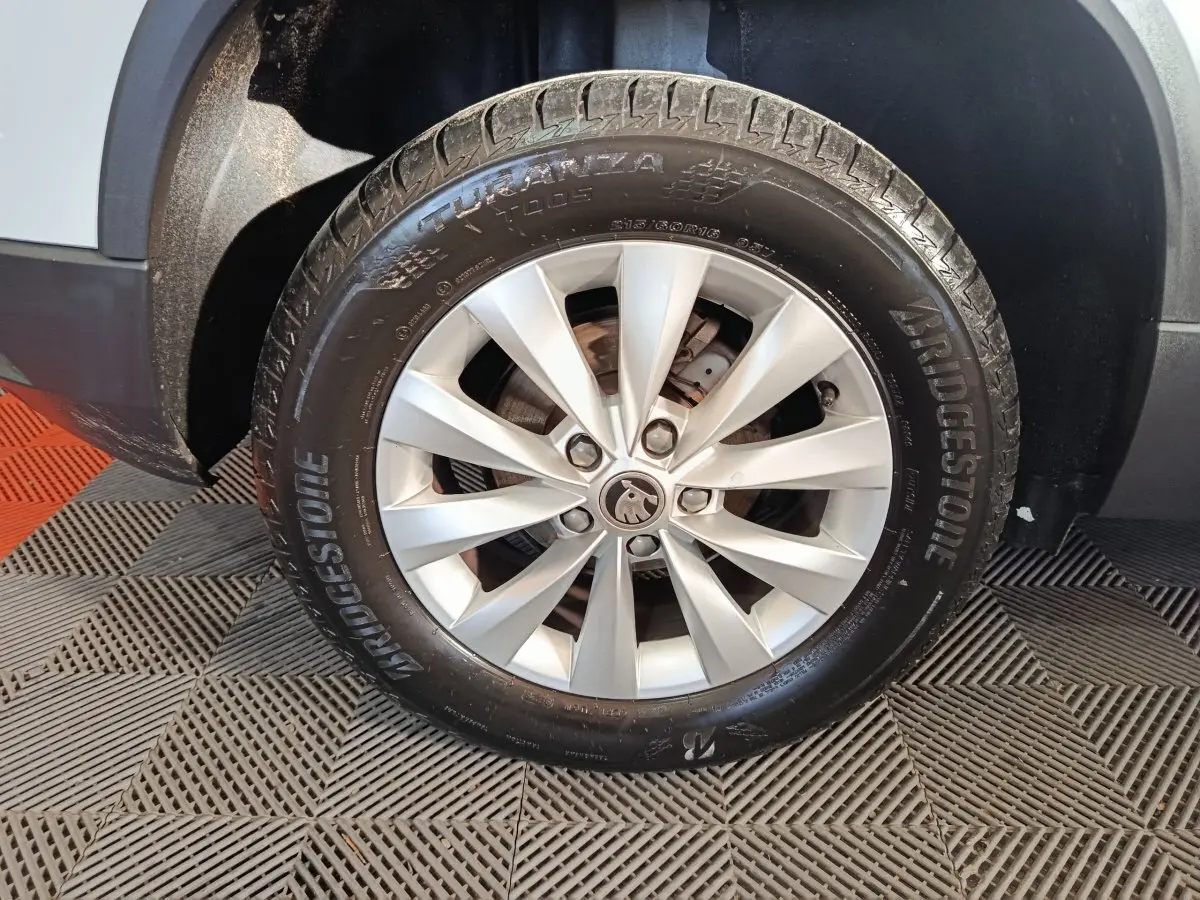 Gros plan sur la roue avant droite d’un Skoda Karoq blanc avec jante argentée et pneu Bridgestone.