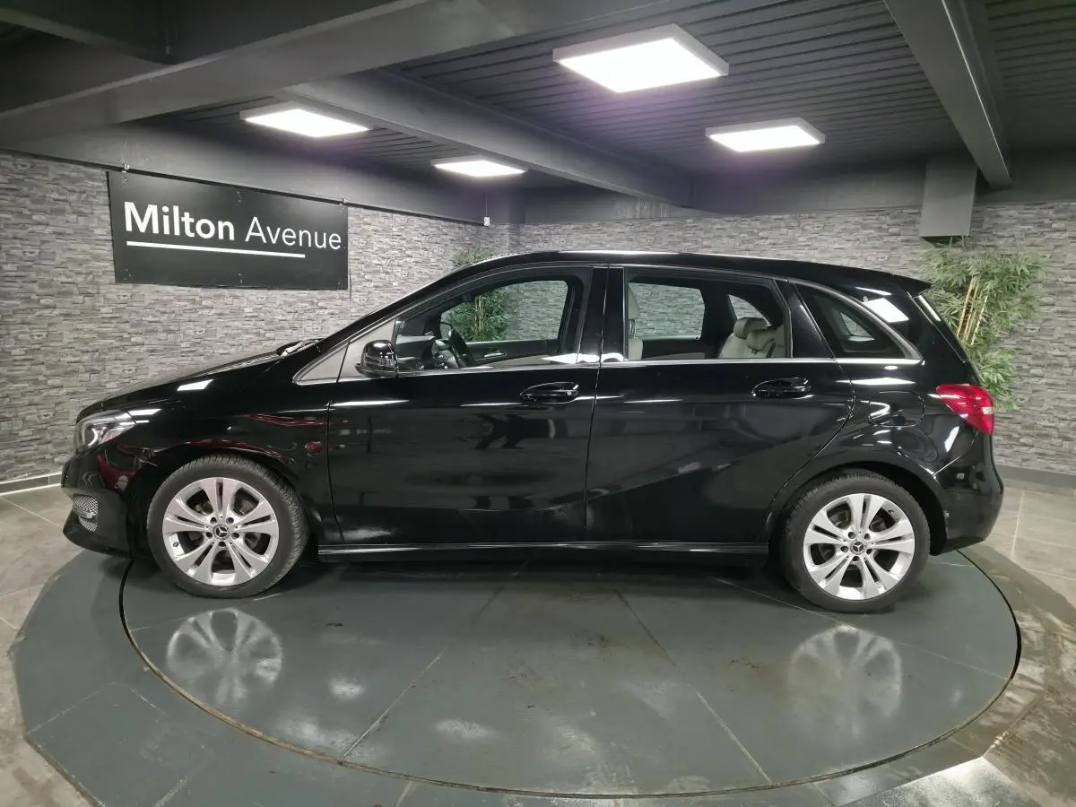 Vue de profil côté gauche d'une Mercedes Classe B noire avec jantes alliage 17 pouces dans un showroom.