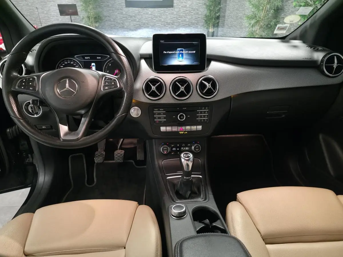 Vue intérieure avant de la Mercedes Classe B 180 d Intuition 2018, volant cuir, console centrale avec boîte manuelle et écran multimédia.