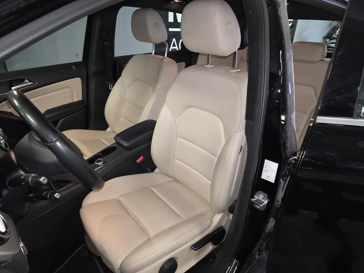 Vue intérieure côté conducteur de la Mercedes Classe B 180 d Intuition noire avec sièges avant en similicuir beige.